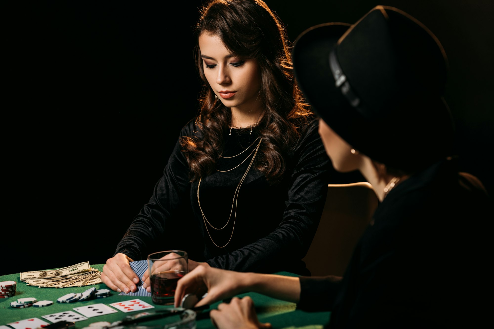 beautiful women in black clothes playing poker at table in casino