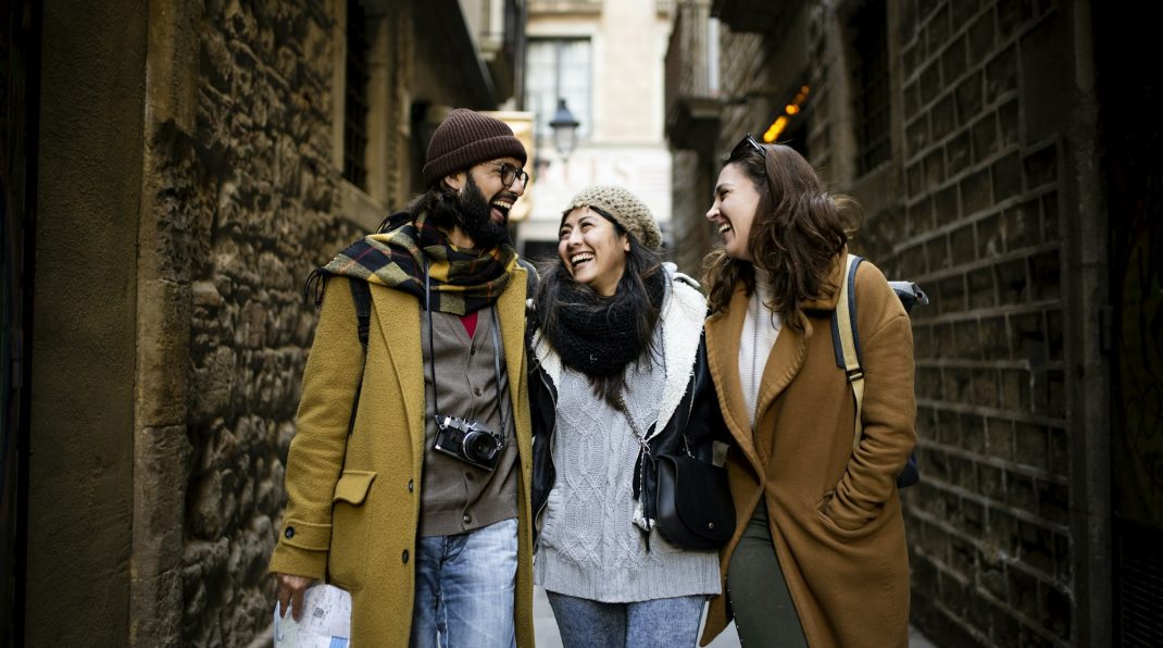 Cheerful multi-ethinc group of friends tourists having fun and walking on the streets of Barcelona -
