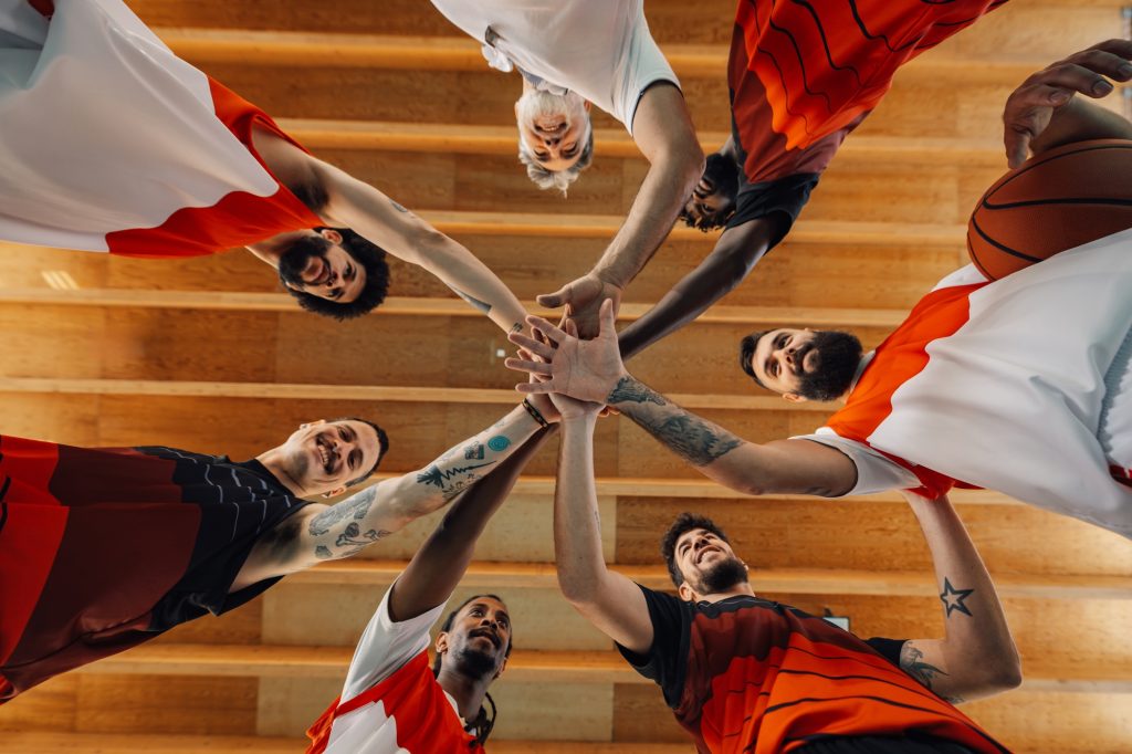 Bottom view of a multicultural basketball players stacking hands on court.