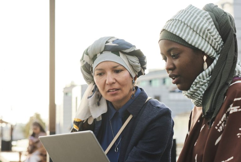 Two refugee women using tablet (Photo via Envato Elements)